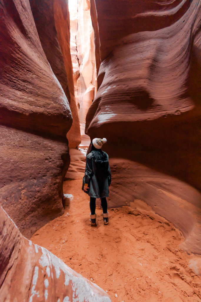 Woman standing inside of red rock slot canyon