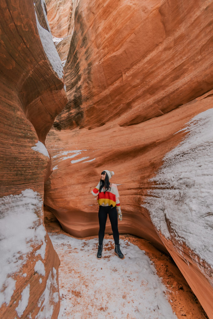 Woman standing inside of red rock slot canyon