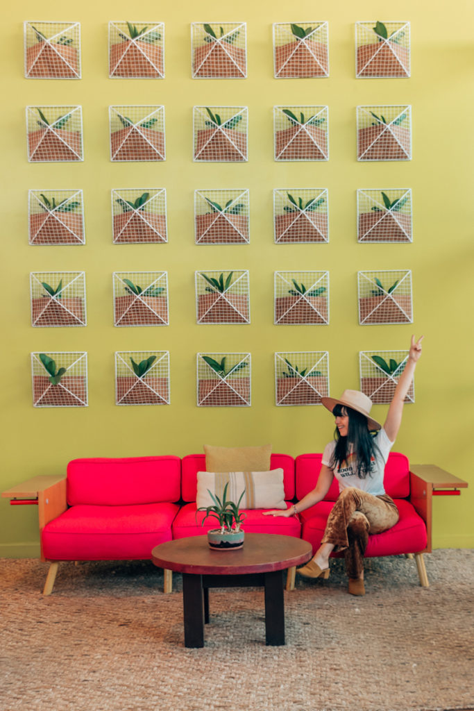 Woman sitting on couch in front of bright yellow wall