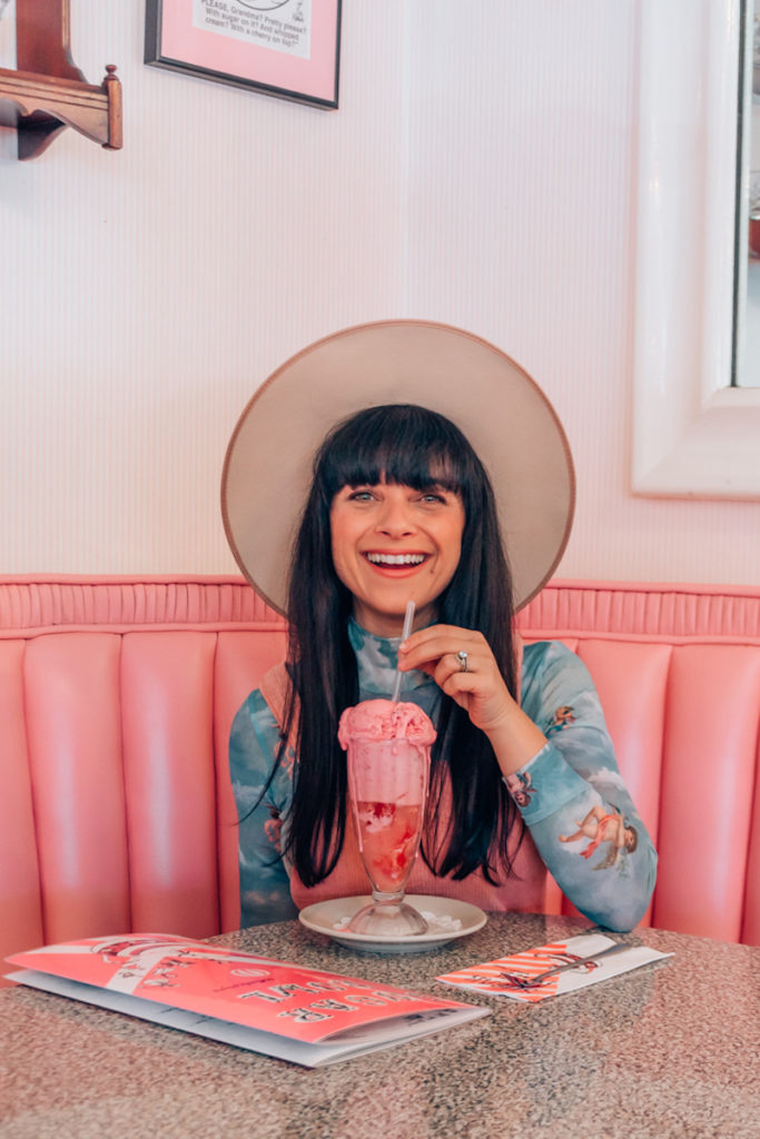 Woman sitting in pink cafe with pink drink