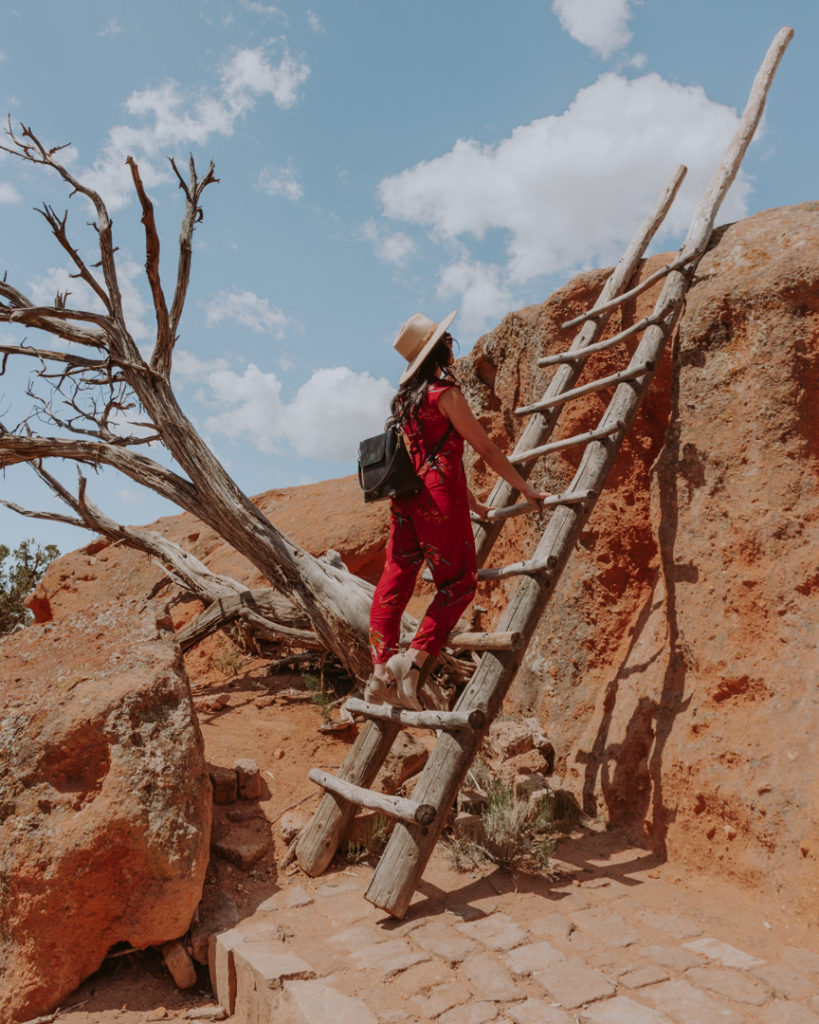 Woman in red jumpsuit climbing wooden ladder