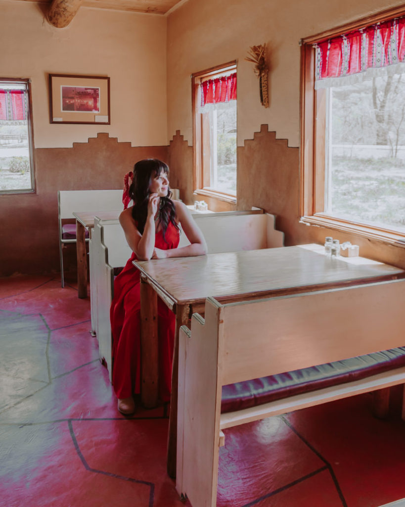 Woman in red dress sitting in restaurant booth at Taos