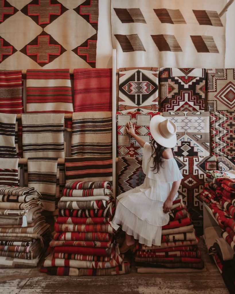 Woman in white dress sitting on Native American rugs