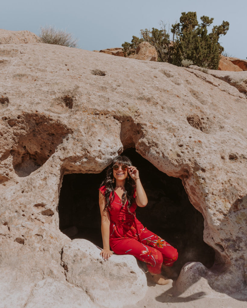 Woman in red jumpsuit in cave dwelling at Bandelier National Monument