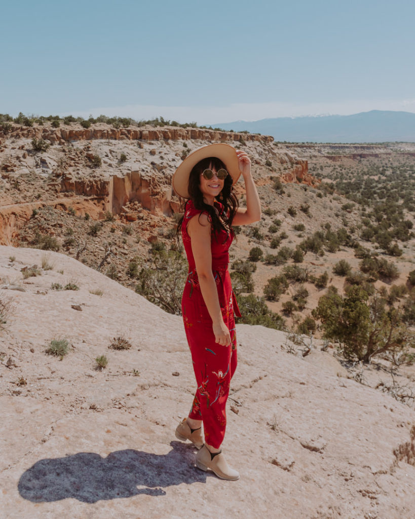 Woman in red jumpsuit and beige hat at Bandolier National Monument