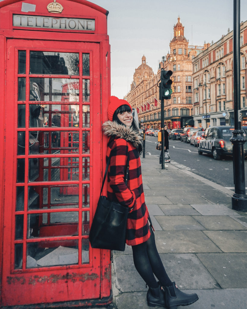 Woman standing in front of red phone booth