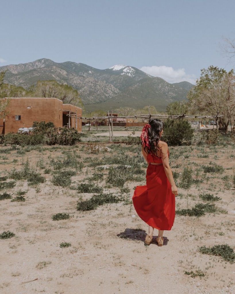 Woman in red dress standing in desert landscape