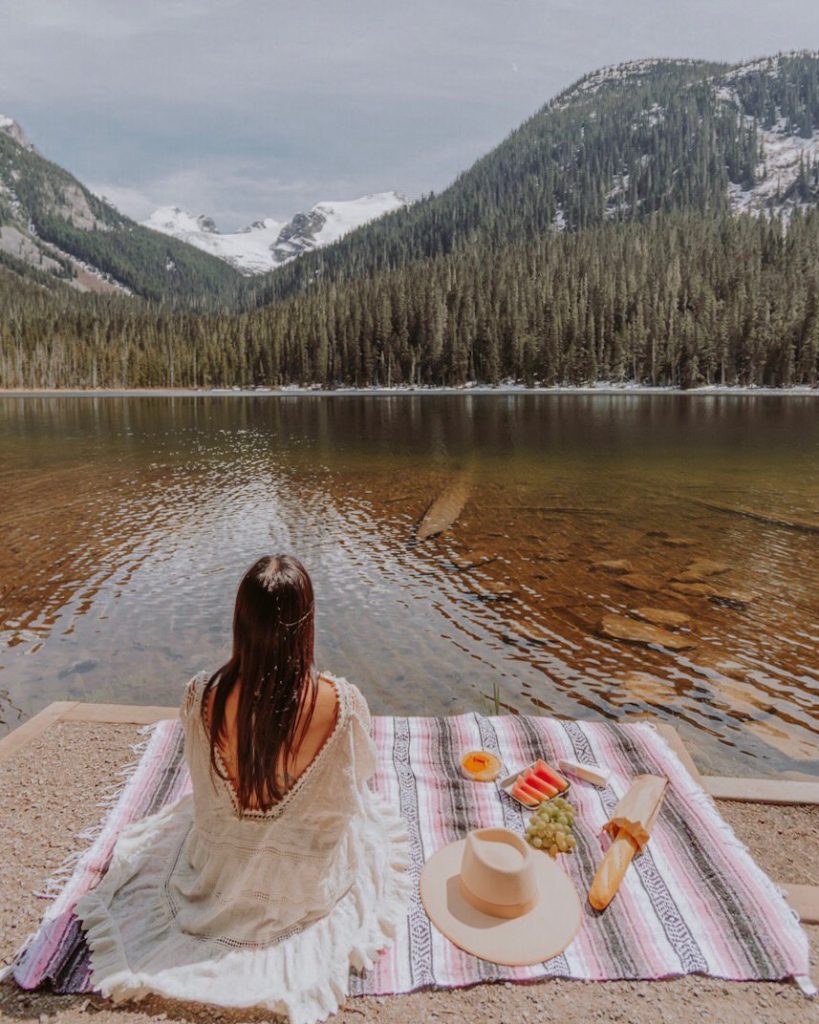 Woman sitting on blanket by lake