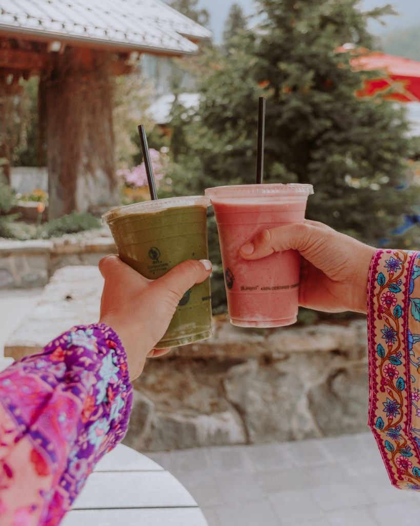 Hands holding pink and green smoothies