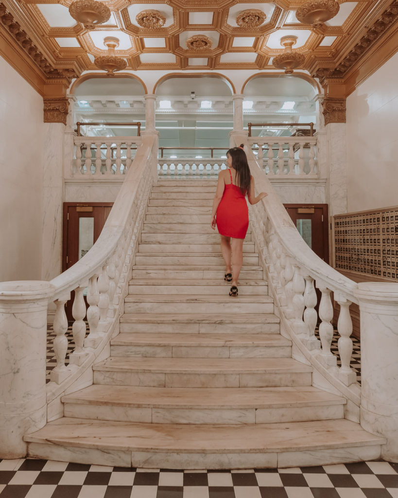 Woman in red dress walking up white staircase