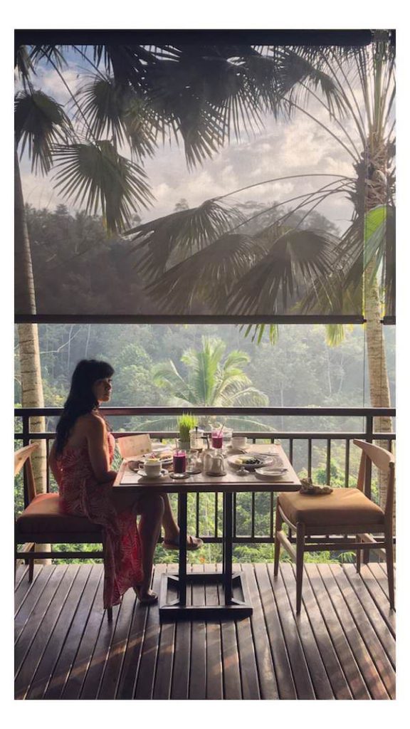 Woman sitting at breakfast table overlooking jungle