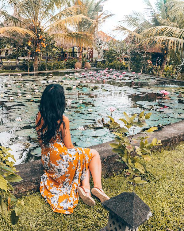 Woman in orange dress sitting by lily pond