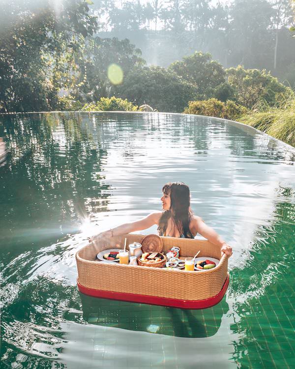 Woman in pool with breakfast on a floating Balinese tray