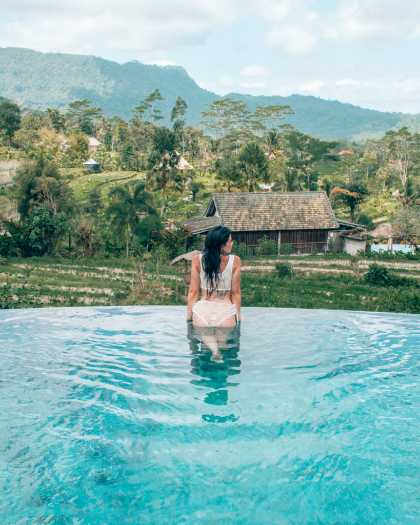 Woman wearing bikini in pool overlooking rice terrace