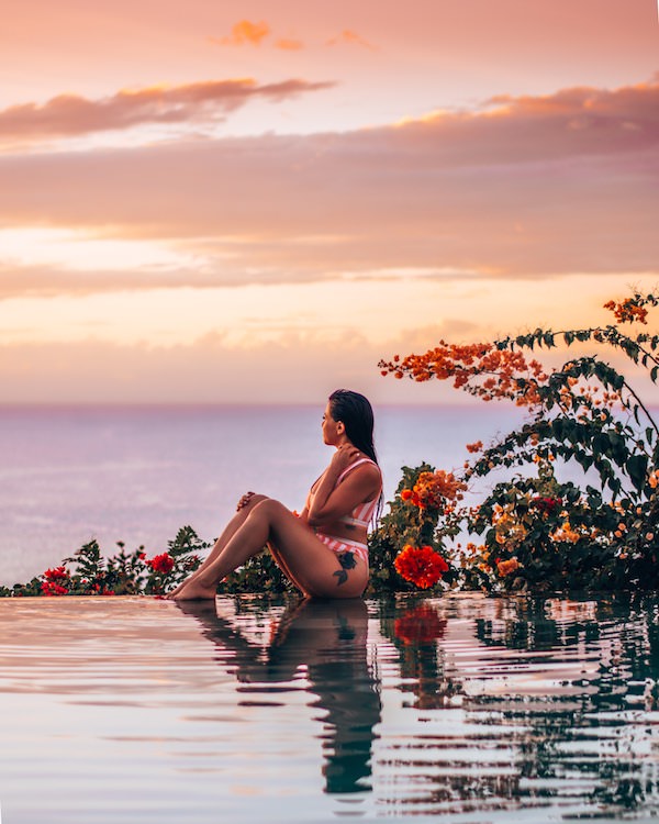 Woman sitting on edge of pool at sunset