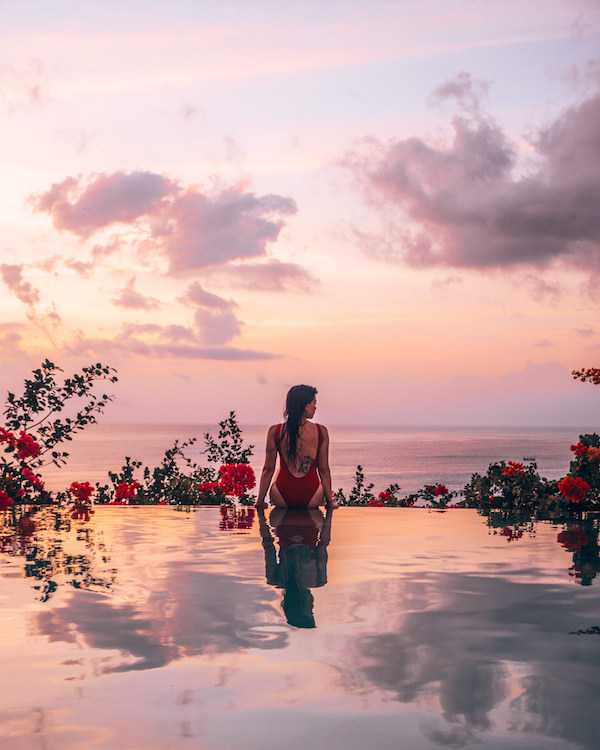 Woman sitting on edge of pool at sunset