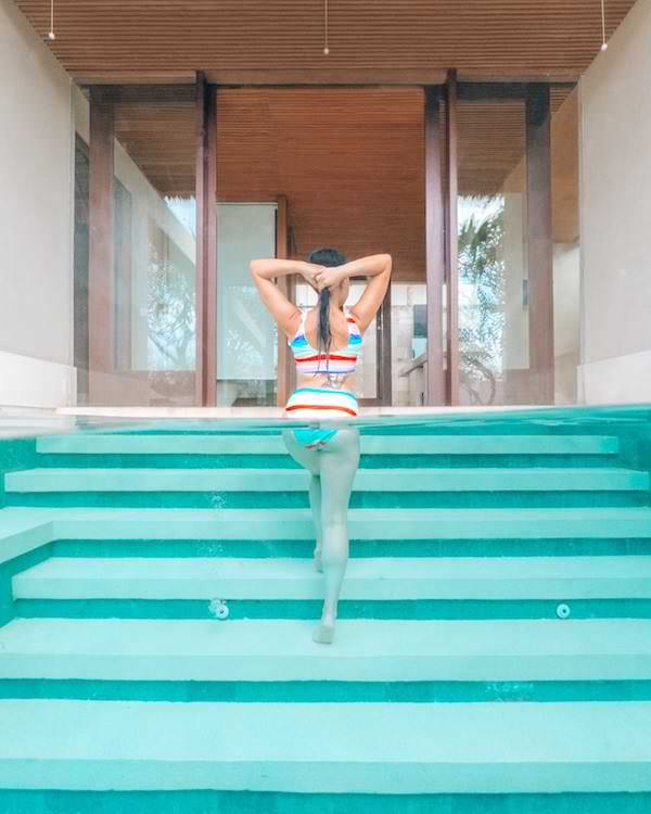 Woman walking staircase from pool into villa