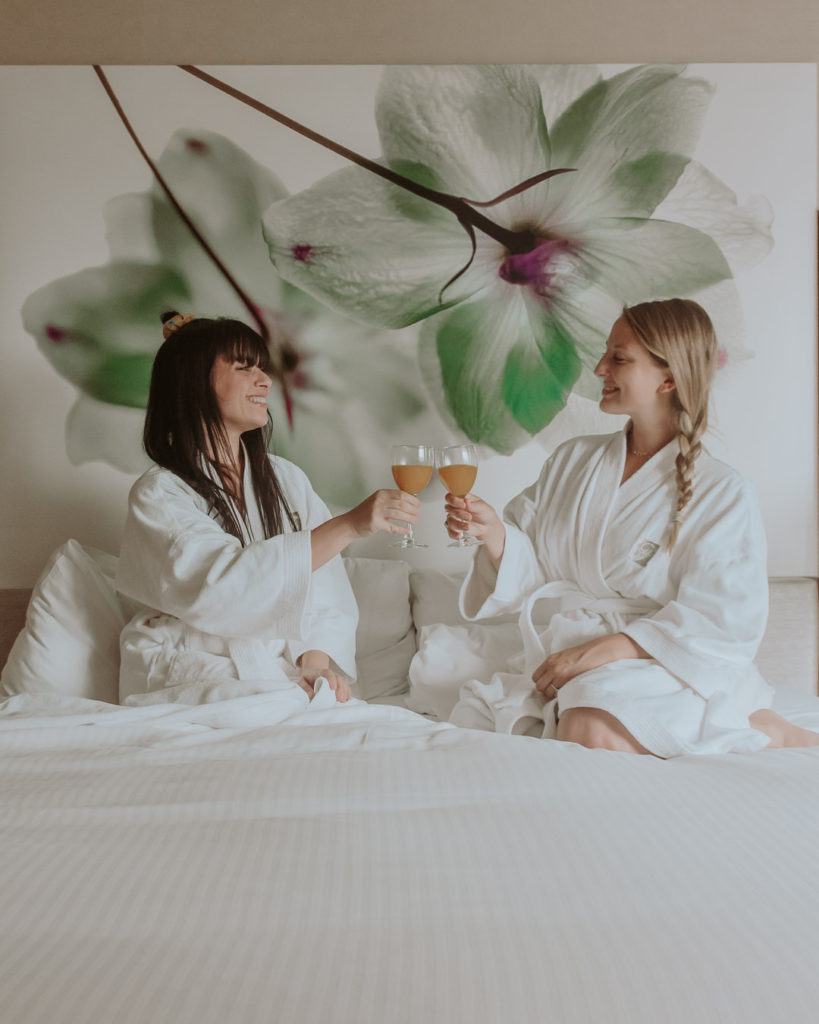 Two women in bathrobes on hotel bed