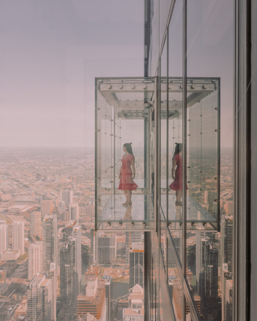 Woman in red dress standing on glass observation deck