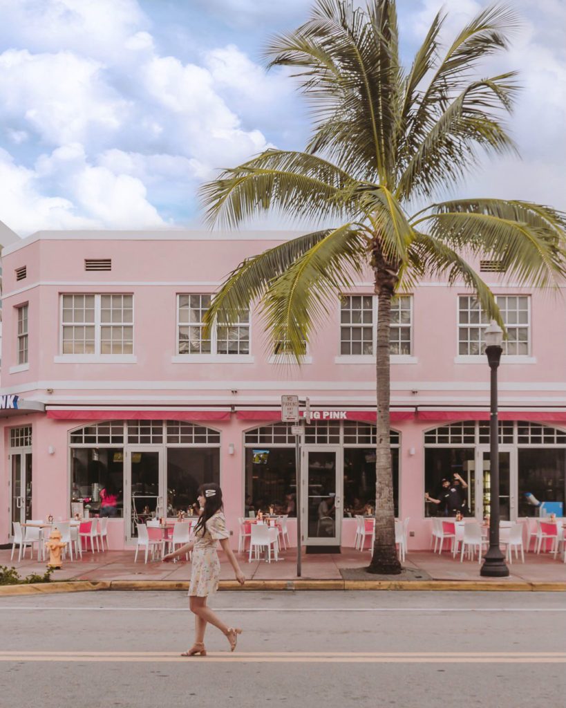 Woman walking in front of pink building