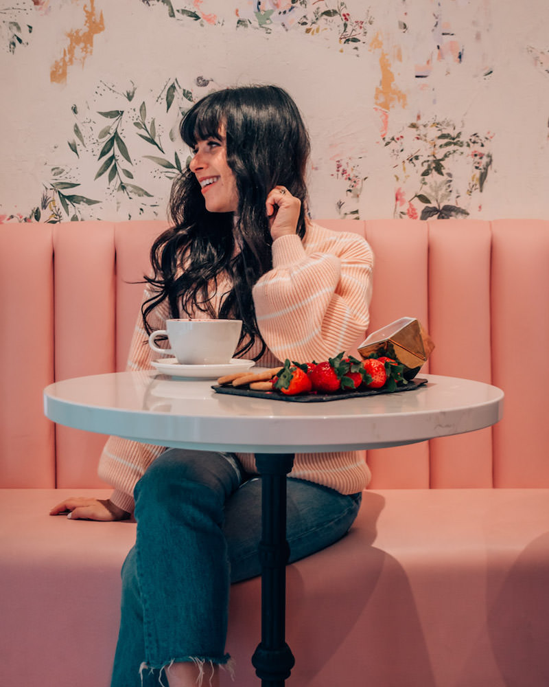 Woman sitting on pink booth in cafe