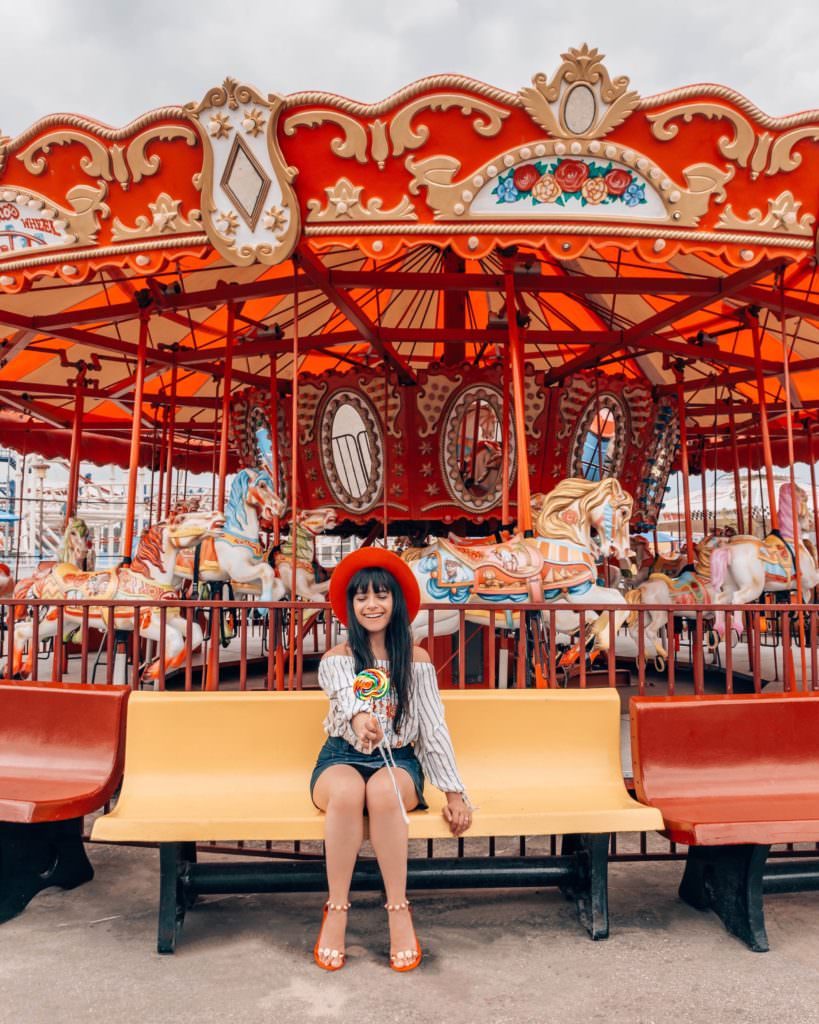 Woman sitting on bench in front of carousel