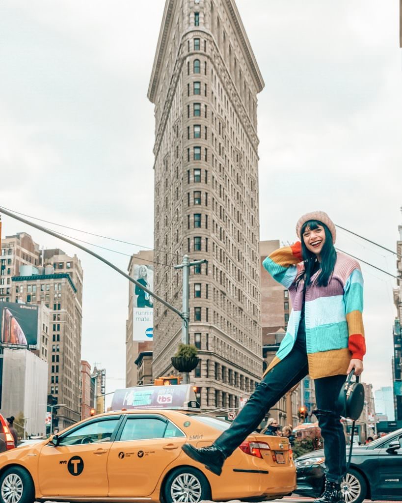 Woman and yellow taxi in front of Flatiron Building
