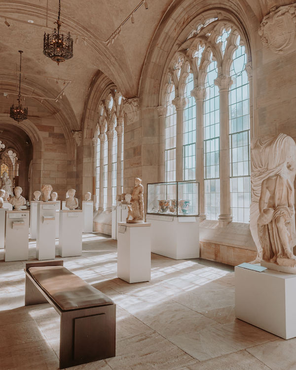Large stone room filled with sculptures and with arched windows 