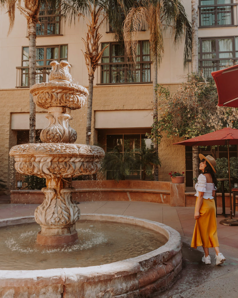 Woman in yellow skirt standing next to fountain