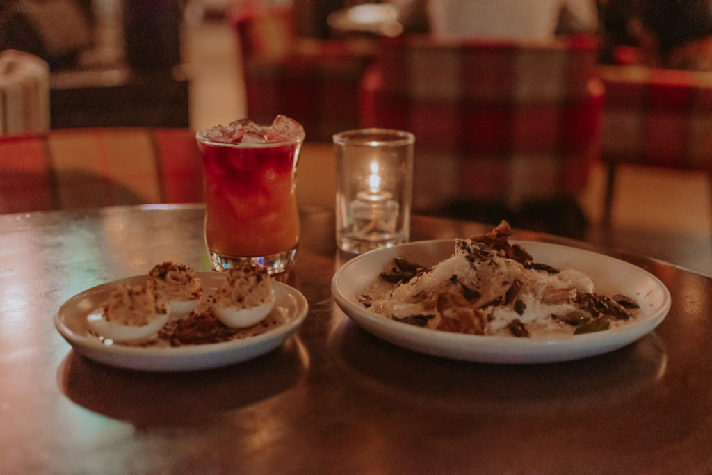 Two plates of appetizers and a cocktail on a restaurant table