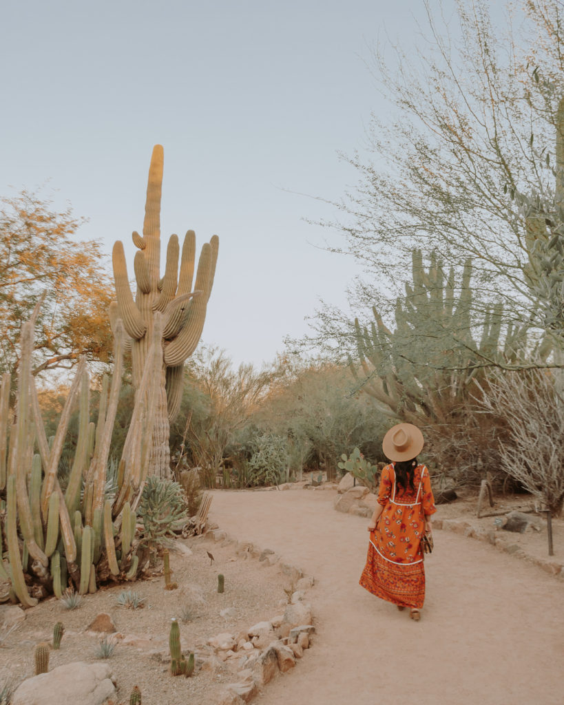 Woman in orange dress walking in botanical gardens
