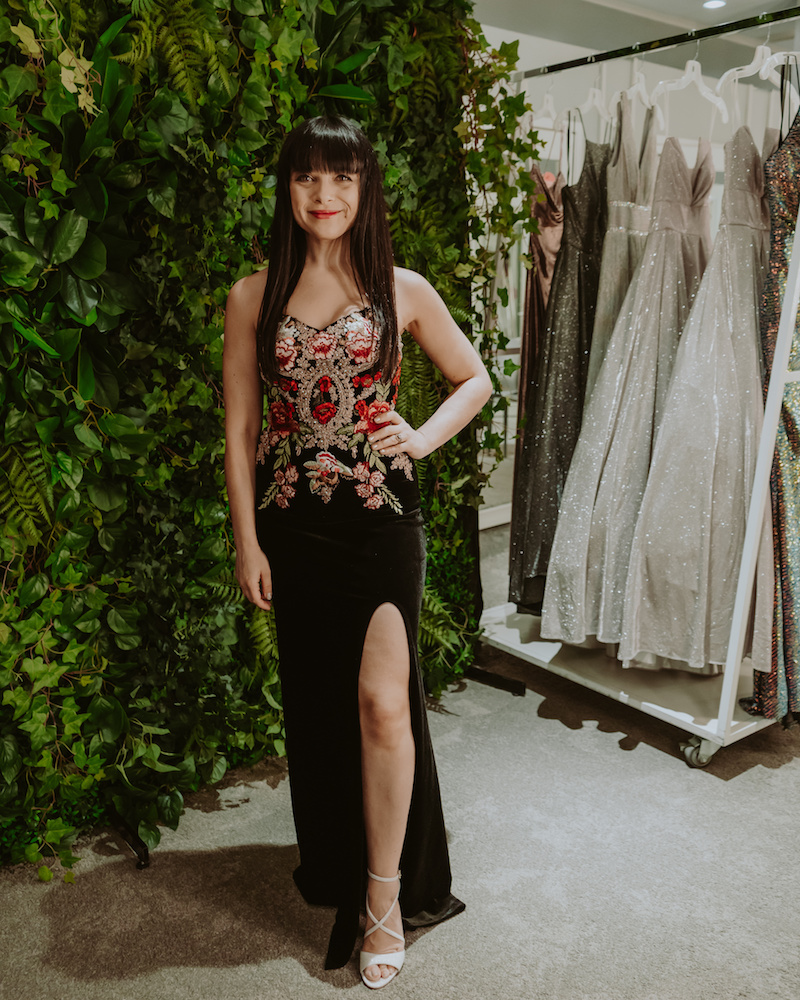 brunette woman wearing long black dress with floral embroidery
