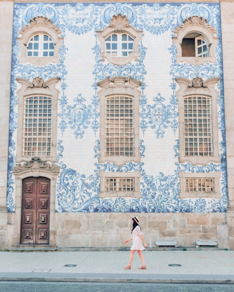 Woman walking in front of blue and white tiled Carmo Church
