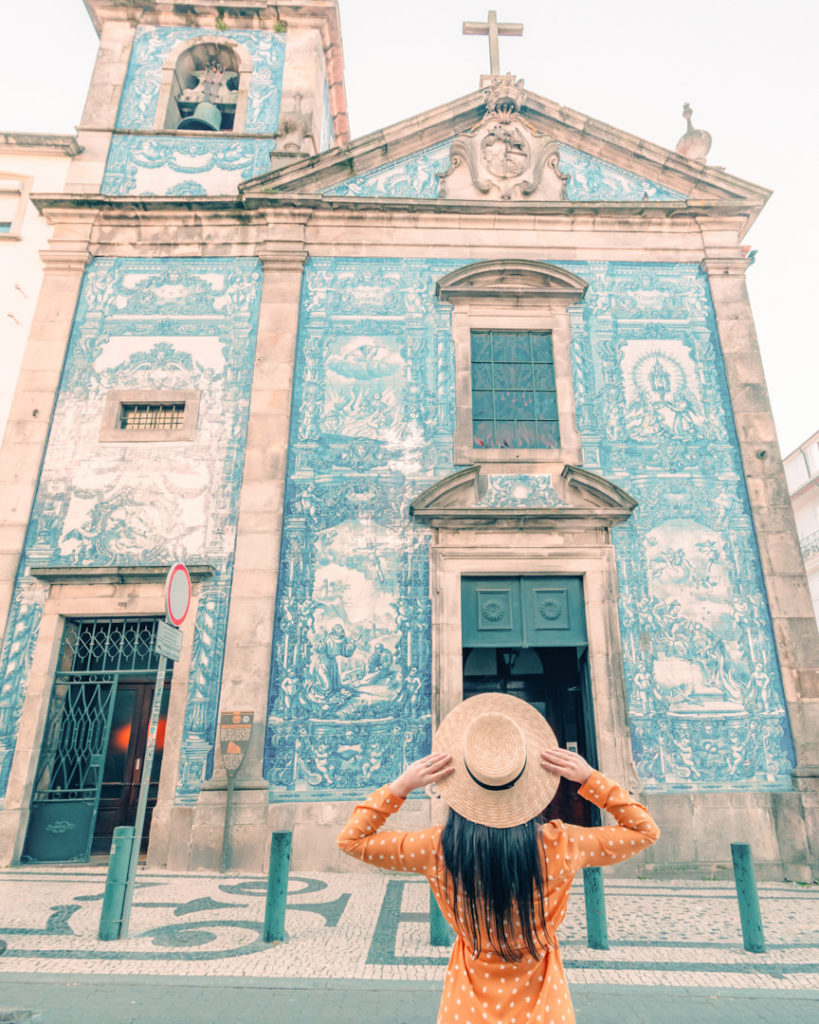 Woman in yellow dress standing in front of blue and white tiled church