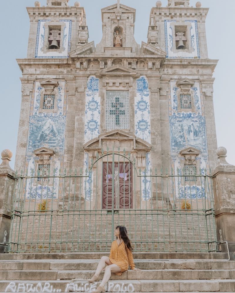 Woman sitting on steps in front of blue and white tiled church
