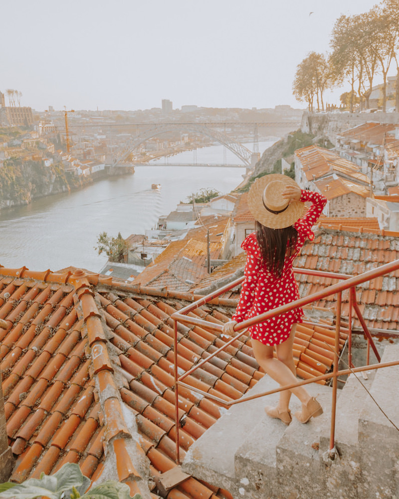 Woman in red dress at Instagram spot in Porto Portugal looking at view of the river