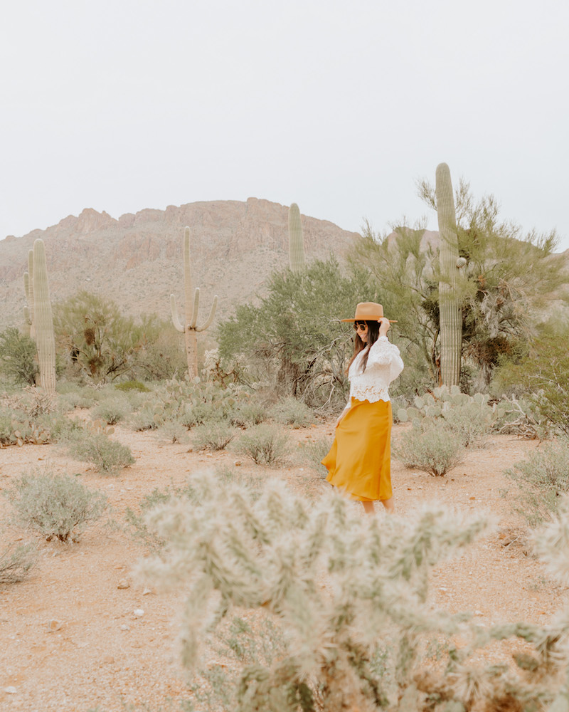 Woman in yellow skirt standing in desert landscape