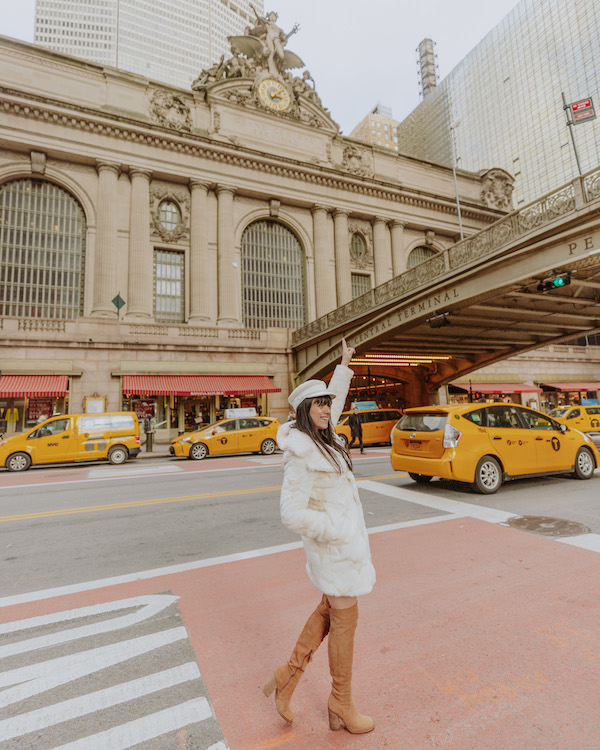 Woman in white jacket hailing NYC yellow taxi