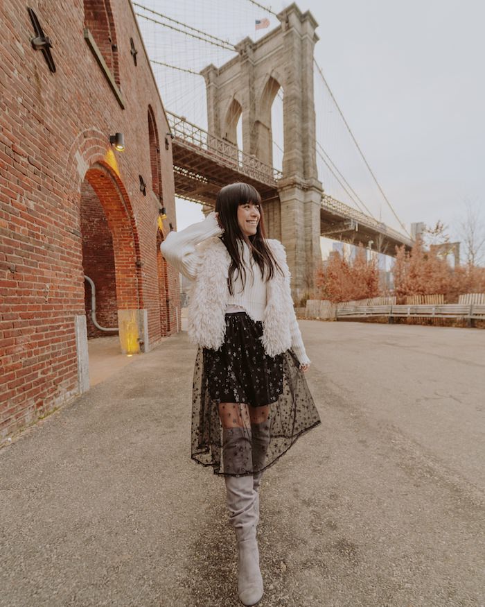 Woman in black skirt walking past Brooklyn Bridge
