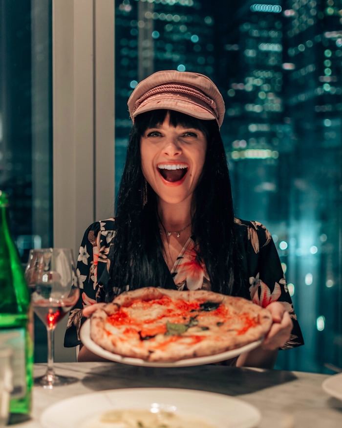 Woman smiling and holding a pizza