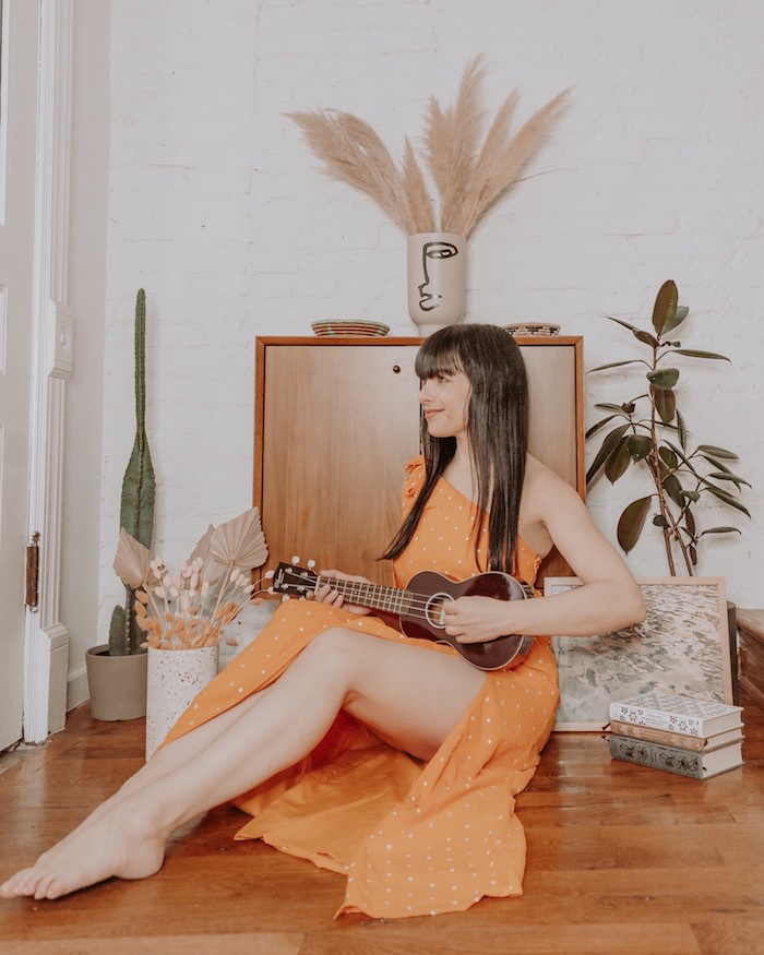 props for photoshoots  - woman in orange dress playing ukulele