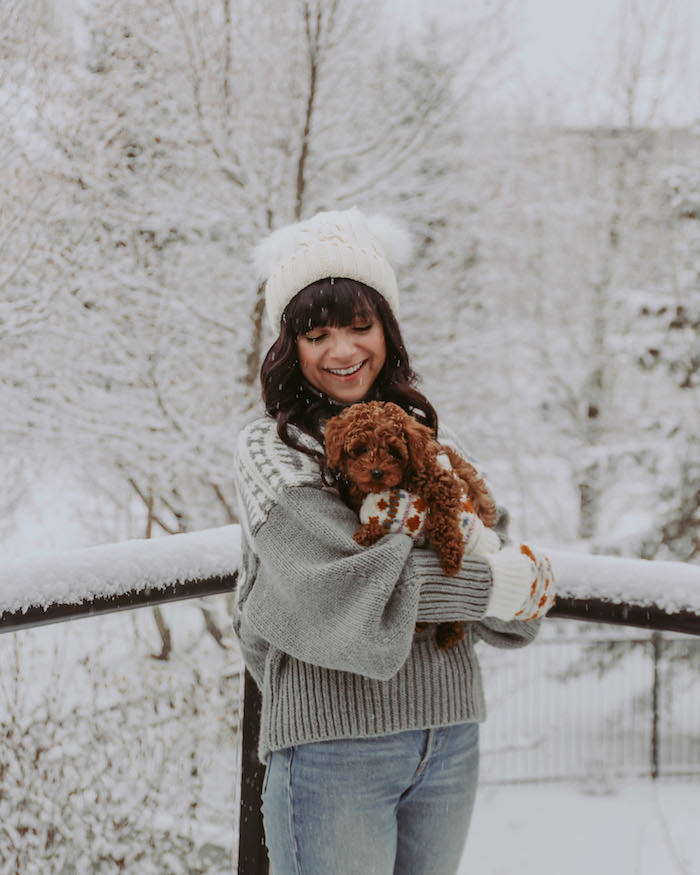 woman outside in snow holding small dog