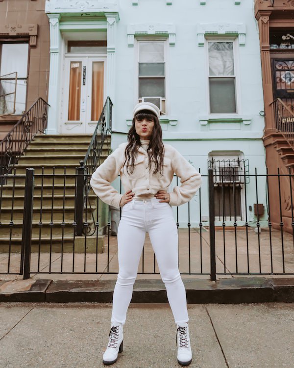 how influencers make money: woman in white jeans standing in front of blue house