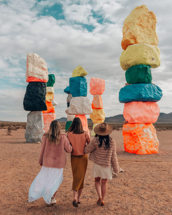 three women walking in front of large colorful art installation