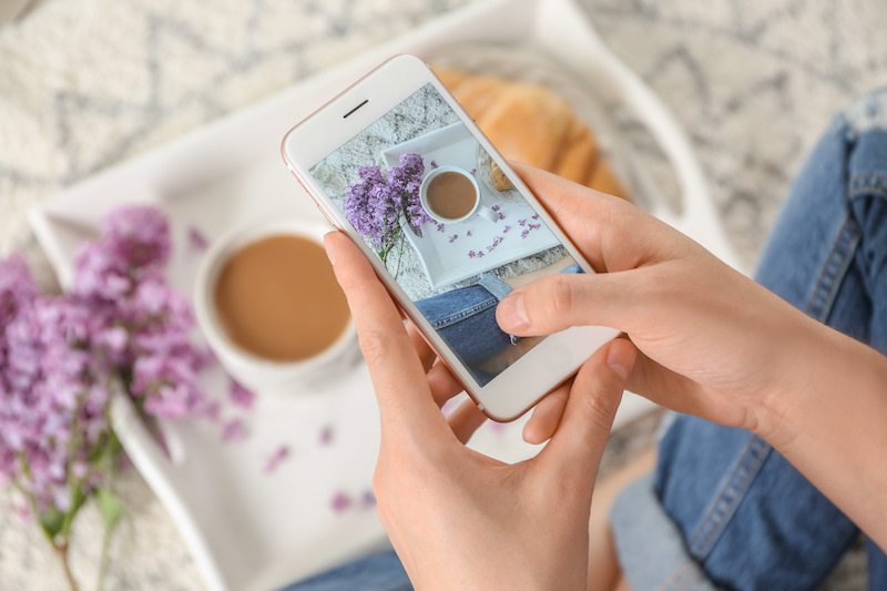 White iphone  and woman's hands taking photo of lavender flowers and coffee
