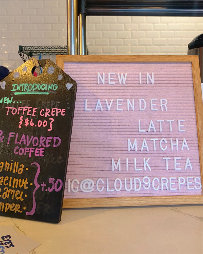 Close up of pink letterboard and black board or a cafe advertising their lavender lattes and other specialty drinks.