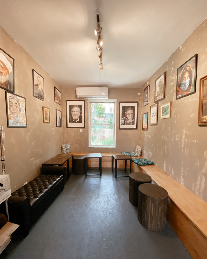 Interior of a coffee shop seating area with beige walls, dark leather benches and framed photos on the walls.