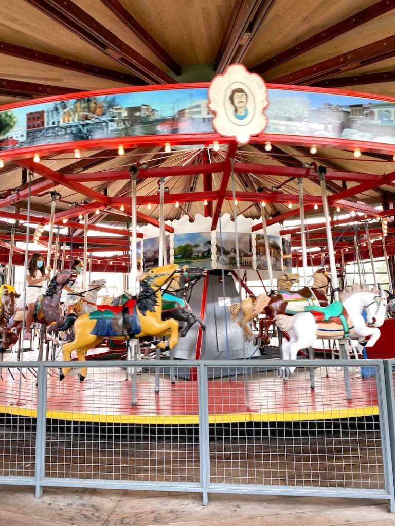 An antique carousel in Greenport, NY that is mostly red, blue and yellow with antique carousel horses 