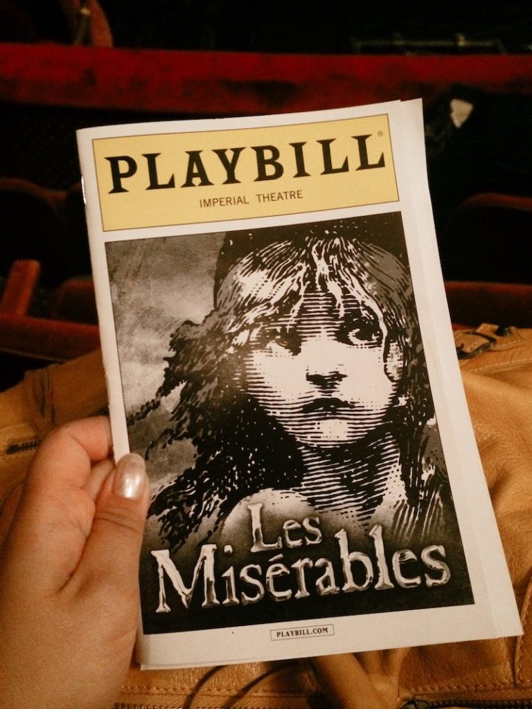 A woman's hand holding a playbill for the broadway show Les Miserables