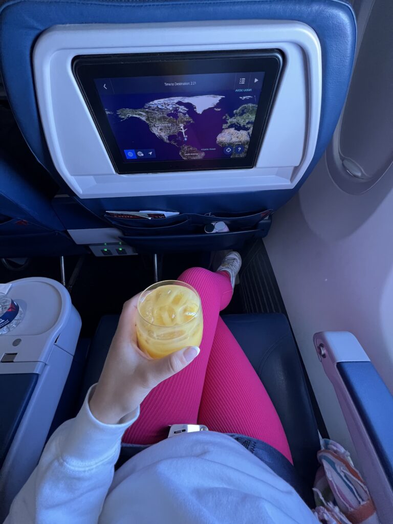 Overhead view of a woman's legs. She is wearing pink leggings and sitting with her legs crossed on an airplane.